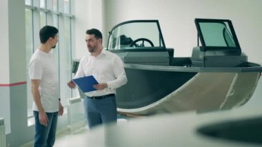 Satıcı, motorlu tekne dükkanında bir alıcıyla konuşuyor.