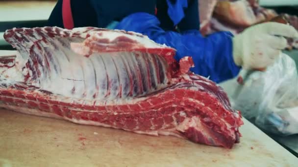 Un trabajador corta carne en la planta de envasado de carne. — Vídeos de Stock