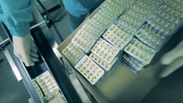 Таблетки в волдырях упаковывают в коробку. Производство лекарственных средств на фармацевтическом заводе. — стоковое видео