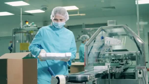 Batches of pills are getting packed into boxes by a female worker — Stock Video