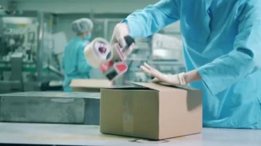 İlaç işçisi koli bandıyla bir kutuyu kapatıyor.