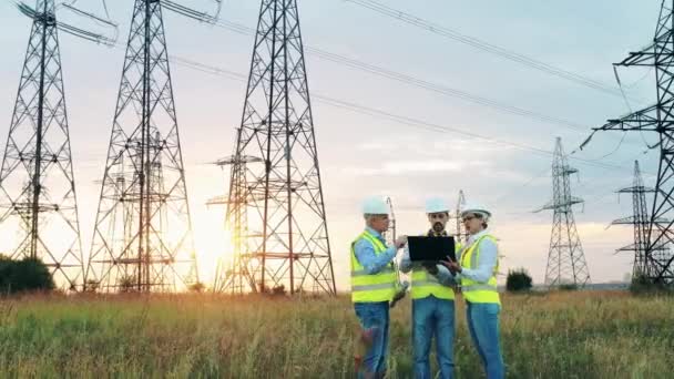 Industria elettrica, concetto di produzione di energia elettrica. I lavoratori dell'energia discutono il lavoro vicino alle linee elettriche. — Video Stock
