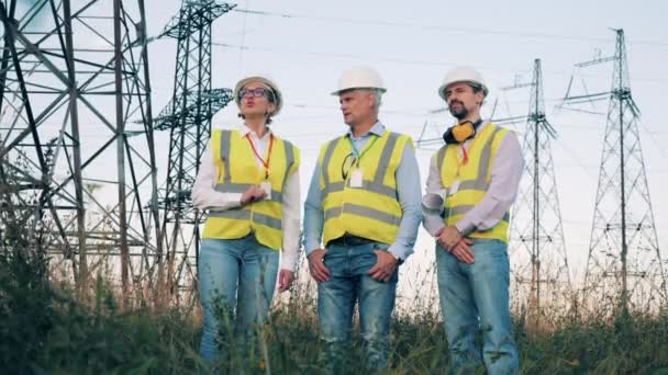 Mulher e homens discutem trabalho perto de linhas de energia. — Vídeo de Stock