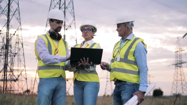 Engenheiros profissionais trabalham com laptop perto de linhas de energia. — Vídeo de Stock