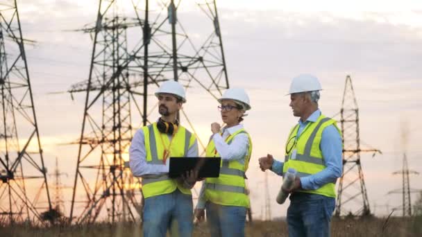 Elektriska arbetare diskuterar arbete, står på elnät bakgrund. — Stockvideo