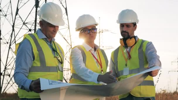 Drei Energiearbeiter sprechen während der Arbeit auf einem Feld. — Stockvideo