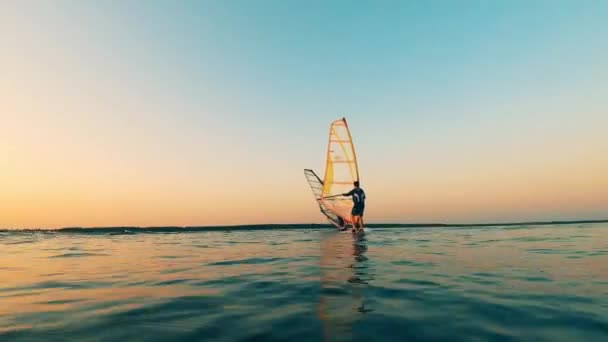 Lac du coucher du soleil avec un groupe de personnes flottant sur la planche à voile — Video