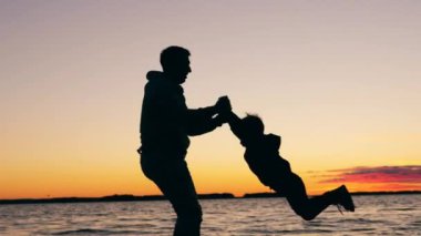 Babası çocuğunu gölün etrafında döndürüyor.