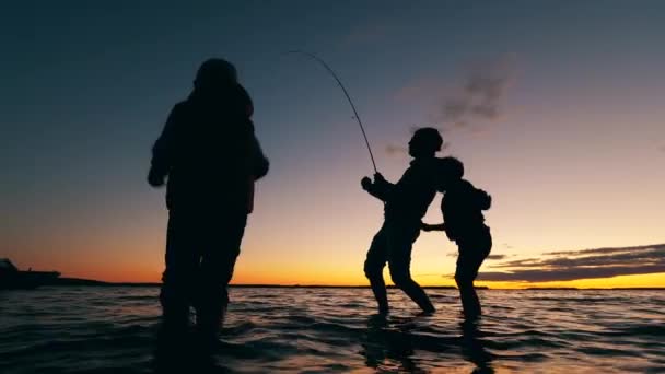 Un hombre captura peces y sus hijos se divierten. — Vídeos de Stock