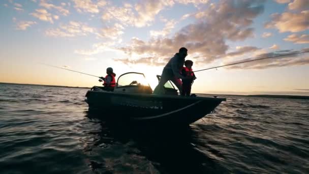 A father is helping his kids with fishing from a boat — Stock Video