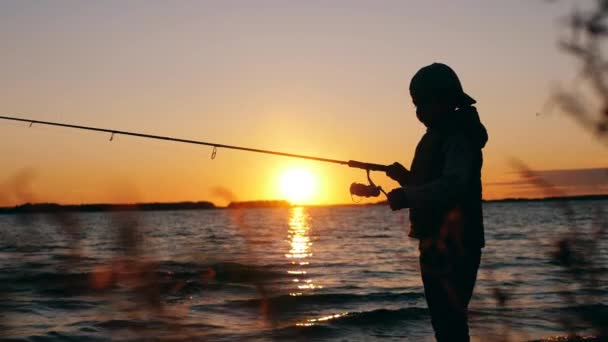 Tramonto lago e un bambino che gestisce una canna da pesca — Video Stock