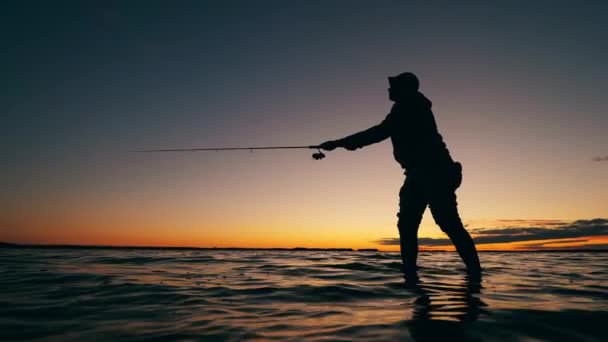 Solnedgång sjö med en manlig fiskare med hjälp av en fiskespö — Stockvideo