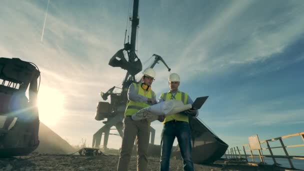 Två ingenjörer har en diskussion nära byggarbetsplatsen, stenbrott. — Stockvideo