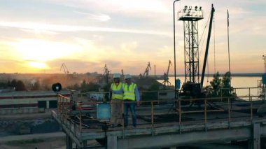 İki uzman yükleme platformunda durup etrafa bakınıyorlar.