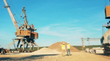 Endüstriyel yükleyiciler gün ışığında bir nehir limanında çalışıyorlar.