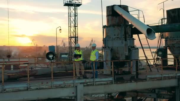 Industriële haven met twee deskundigen in gesprek bij zonsondergang — Stockvideo