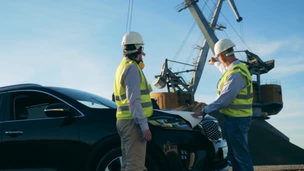 Ingenieros están hablando de planes cerca de un coche y un cargador industrial — Vídeos de Stock