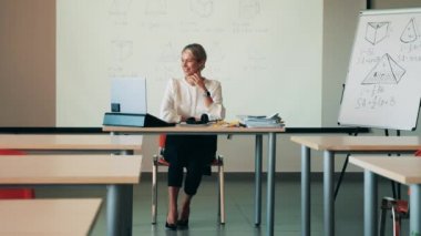 Bir bayan boş sınıfta online ders veriyor.