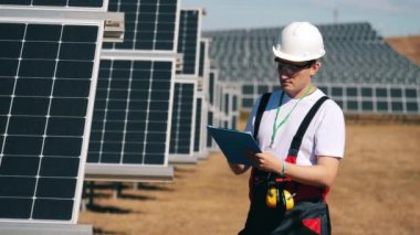 Erkek mühendis güneş pillerini kontrol ediyor. Yenilenebilir enerji, güneş santrali, yeşil elektrik kavramı.