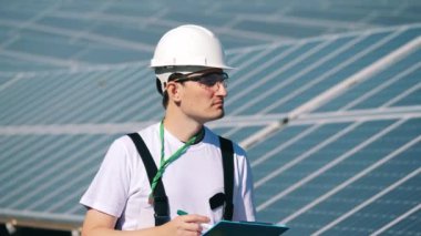 Bir adam açık hava güneş panellerini teftiş ediyor. Yenilenebilir enerji, güneş santrali, yeşil elektrik kavramı.