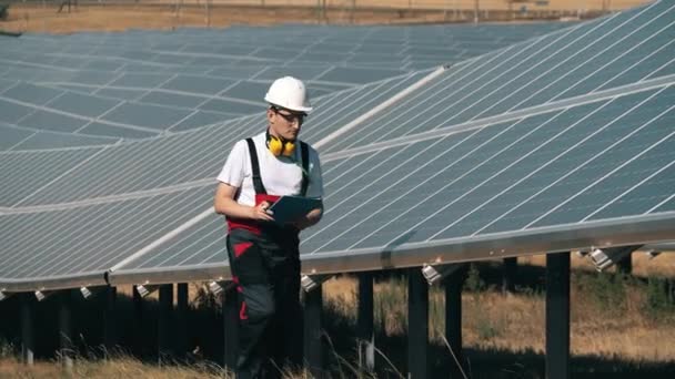 Technik kontroluje solární panely. Pracovník alternativní energie v blízkosti solární elektrárny. — Stock video