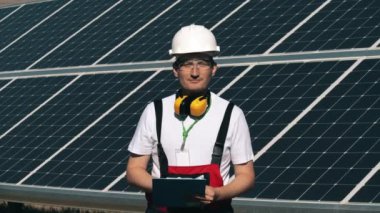 Güneş mühendisi kameraya bakıyor ve gülümsüyor. Güneş enerjisi mühendisinin portresi.