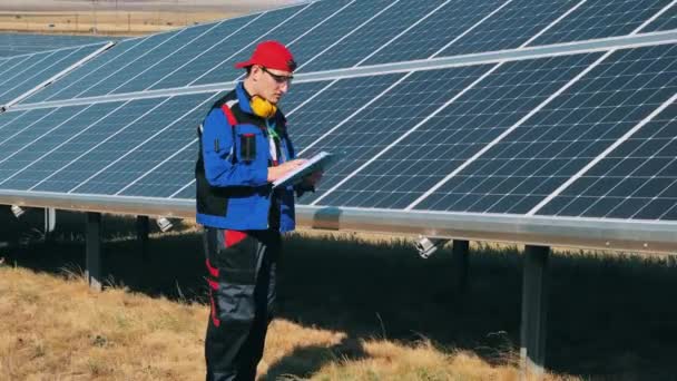 Erkek mühendis güneş panellerini inceliyor. Yenilenebilir enerji, güneş santrali, yeşil elektrik kavramı. — Stok video
