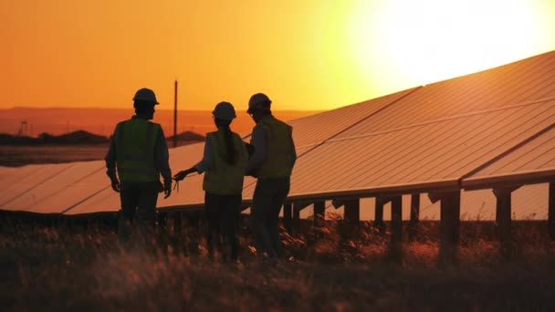 Obnovitelná energie, solární elektrárna, koncept zelené elektřiny. Sluneční panely zapadají za soumraku a technici je míjejí — Stock video