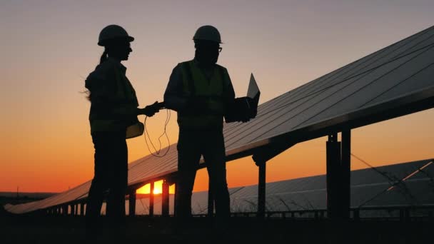 Dos ingenieros solares están hablando de baterías al atardecer — Vídeos de Stock