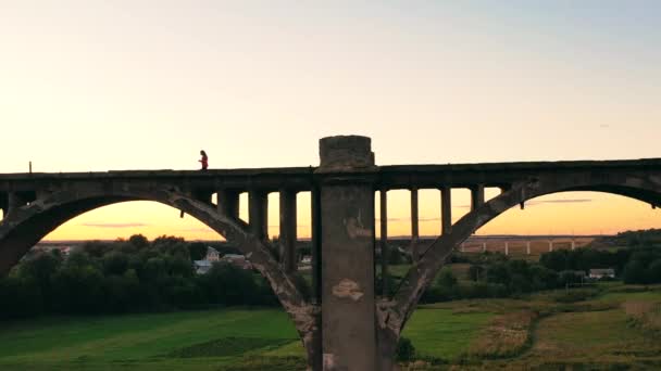 Una corredora cruzando un viejo puente está siendo filmada desde lejos. — Vídeos de Stock