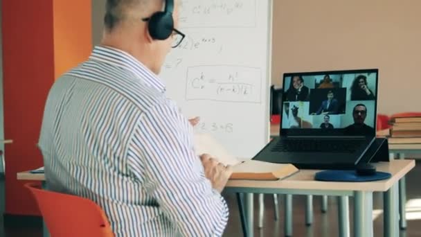 Ein Mann demonstriert Schülern während des Online-Unterrichts ein Buch. Online-Lernen, Online-Bildung, Fernstudium, Fernlehrkonzept. — Stockvideo