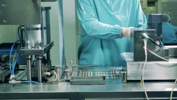 Muž pracuje v lékařské laboratoři, kontroluje kapsle. Výrobní linka farmaceutické továrny. — Stock video