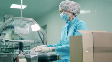 Asyalı etnik kadın konveyör üzerinde ilaçlarla çalışıyor.