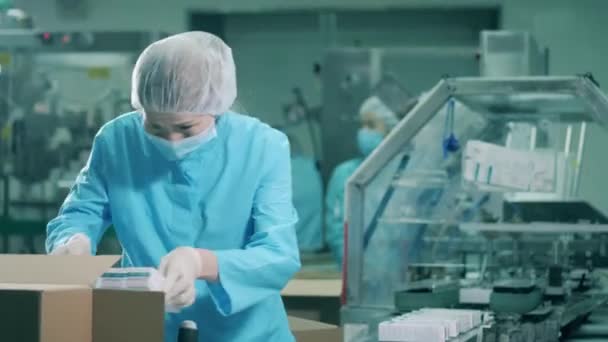 Asiatisk etnisk kvinnlig farmaceut packar botemedel i lådor. Produktionslinje för läkemedelsfabriker. — Stockvideo