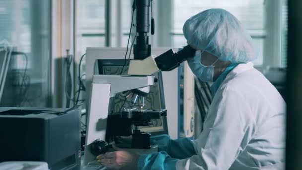 Kadınlar laboratuvarda mikroskopla çalışıyor. Modern bir eczacılık tesisinde ilaç üretim hattı.. — Stok video