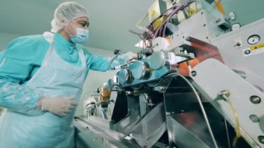 Adam laboratuarda bir taşıma makinesiyle çalışıyor. Modern bir tesiste ilaç üretim hattı..