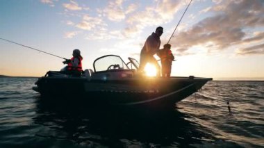 Küçük çocuklar babalarıyla bir tekneden balık tutuyorlar.