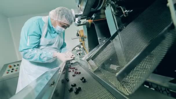 Il farmacista maschio controlla le capsule scure in laboratorio. Linea di produzione farmaceutica in un moderno stabilimento farmaceutico. — Video Stock