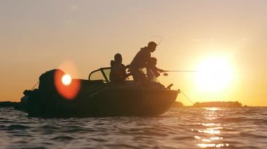 Bir adam oğullarının tekneden balık yakalamalarına yardım eder.