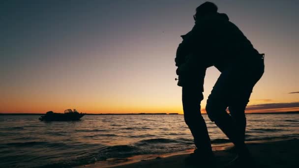 Père enseigne à son fils à attraper du poisson au coucher du soleil — Video