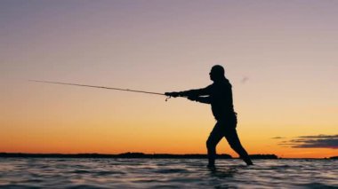 Balıkçı suda duruyor ve balık yakalıyor.