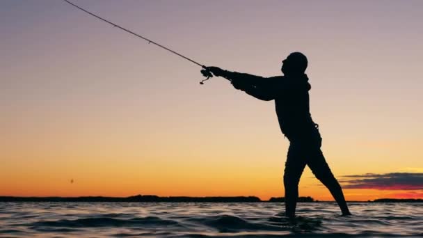 Lago pôr do sol e um pescador lançando um pólo de pesca — Vídeo de Stock