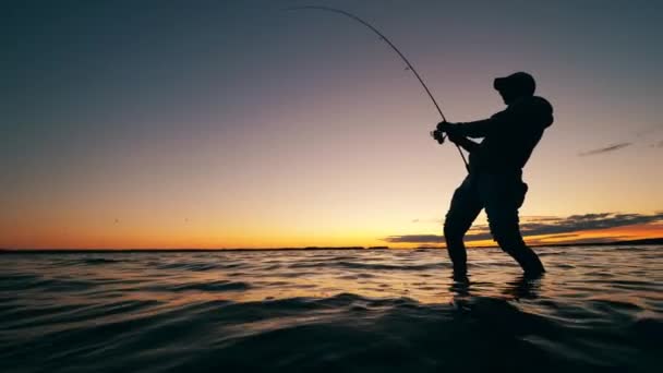 Lac au coucher du soleil avec un pêcheur mâle attrapant le poisson — Video