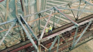 Mühendislik işçileri inşaat tesisi boyunca yürüyorlar.