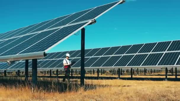 Ηλιακός ηλεκτρικός σταθμός με έναν άντρα εργάτη να περπατά κατά μήκος του — Αρχείο Βίντεο