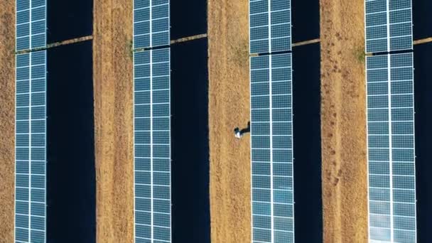 Üzerinde bir adamın yürüdüğü bir güneş enerjisi istasyonunun en üst görüntüsü — Stok video