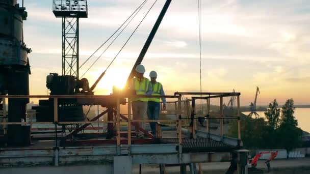 Medewerkers van de mijnbouw lopen langs een massieve metalen constructie — Stockvideo