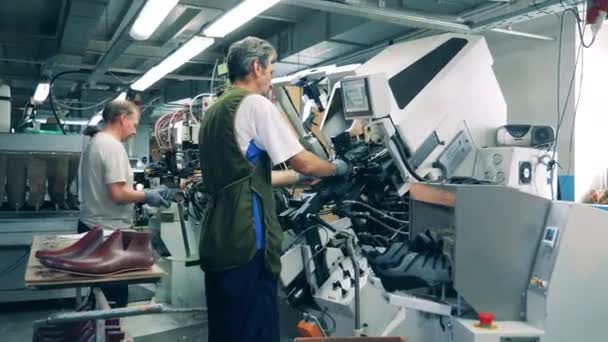 Работники мужского пола используют оборудование для изготовления обуви. Производственные мощности по производству обуви. — стоковое видео