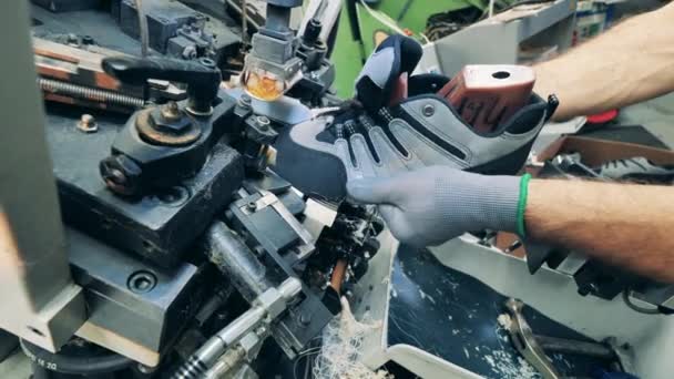 Produktionsanläggning för skodon. Fabriksarbetare använder en maskin för att sätta en sko i form — Stockvideo
