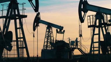 Petrol pompası valelerinin arasında duran petrol işçisi. Petrol endüstrisi, ham petrol fiyatları kavramı.